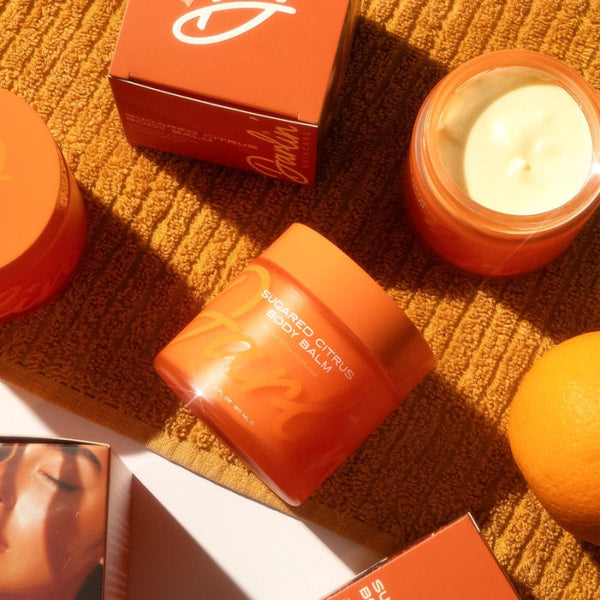 Darlin' Skincare Sugared Citrus Tallow Body Balm in an open orange jar with box on an orange towel | Build A Luxury Custom Gift Box for Women with Luxe & Bloom