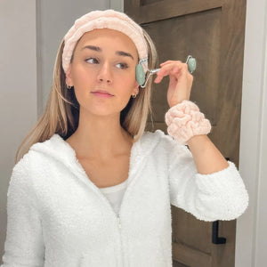 Woman using ESW Beauty Pink Skincare Headband & Wrist Bands and Jade Facial Roller in a bathroom | Build A Luxury Custom Gift Box for Women with Luxe & Bloom