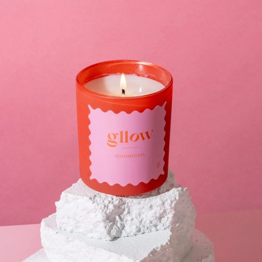 Glow Sentimental Scented candle with a pink label on a white base against a pink background | Build A Luxury Custom Gift Box for Women with Luxe & Bloom