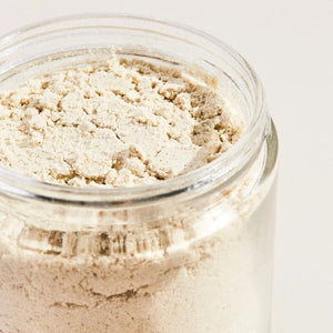 Open jar of Palermo Body Soothing Milk Bath powder on a white background