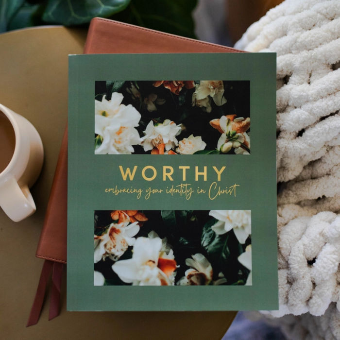 The Daily Grace Co. Devotional called 'Worthy: embracing your identity in Christ' with floral design on a surface.