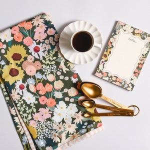 Amy Heitman Flower Market Towel next to the Flower Market Notepad, a cup of coffee, and gold measuring spoons on a white surface | Build A Luxury Custom Gift Box for Women with Luxe & Bloom