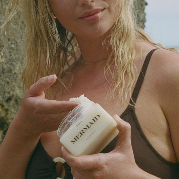 Woman holding a jar of BajaZen Mermaid Body Buff Scrub on a beach | Build A Luxury Custom Gift Box for Women with Luxe & Bloom