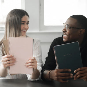 A woman and a man each holding a Church Notes notebook and smiling at each other