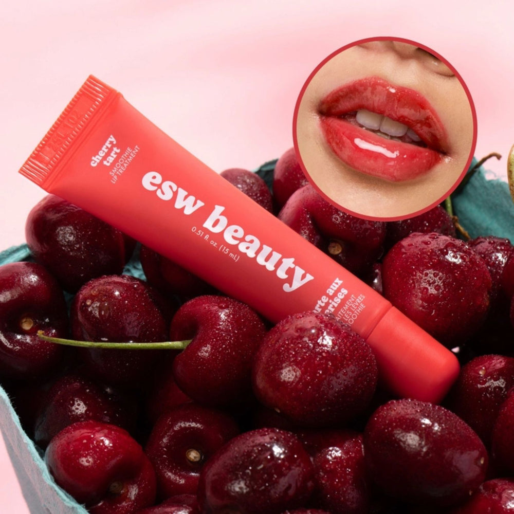 A red squeeze tube of esw beauty cherry tart lip treatment standing in front of a matching red circular swatch on a white background.
