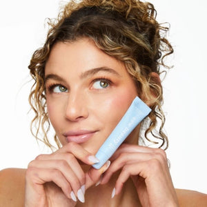 Woman holding blue tube of ESW Beauty White Pitaya Coconut Smoothie Lip Treatment near her face