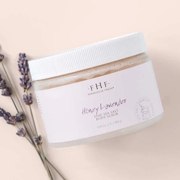 Jar of Farmhouse Fresh Honey Lavender Fine Sea Salt Body Scrub with lavender flowers on a beige background