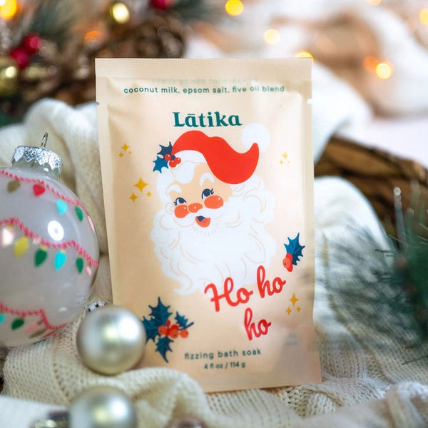 Latika Beauty Santa Fizzing Bath Soak on a festive background with ornaments and lights | Build A Custom Luxury Christmas Gift Box for Women with Luxe & Bloom