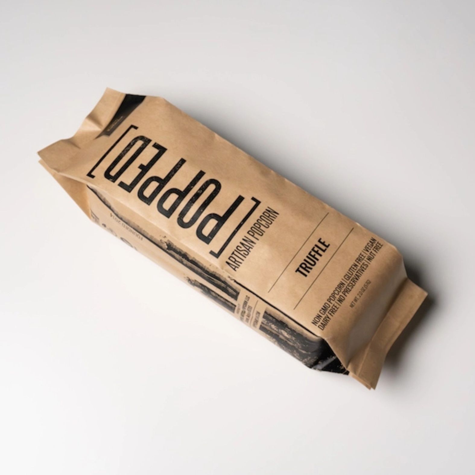 A single bag of Popped Artisan Popcorn in the Truffle flavor, packaged in brown kraft paper with black printed text, photographed on a clean white background | Build A Luxury Custom Gift Box with Luxe & Bloom