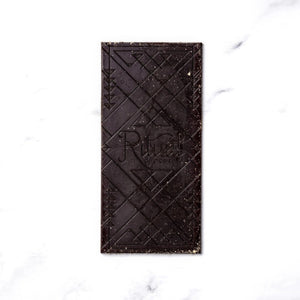 A Ritual S'mores dark chocolate bar with embossed geometric patterns and the brand name 'Ritual' visible in the center, placed on a white marble surface.