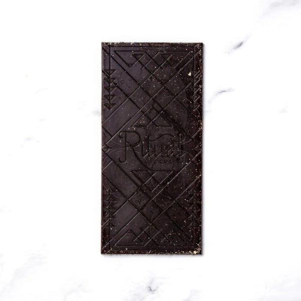 A Ritual S'mores dark chocolate bar with embossed geometric patterns and the brand name 'Ritual' visible in the center, placed on a white marble surface.