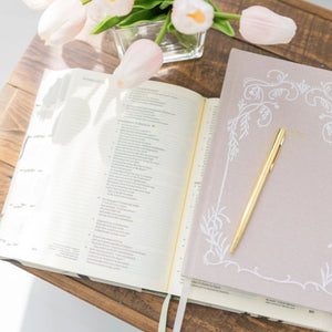 Open Bible with a Selah Publications Lainey Notebook and pink tulips and a pen on a wooden surface