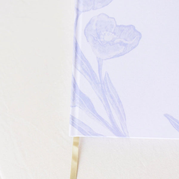 A close up of Selah Publications The Langley Notebook with blue painted flowers and gold lettering on an off-white linen cover with gold ribbon | Build A Christian Custom Gift Box for Women with Luxe & Bloom