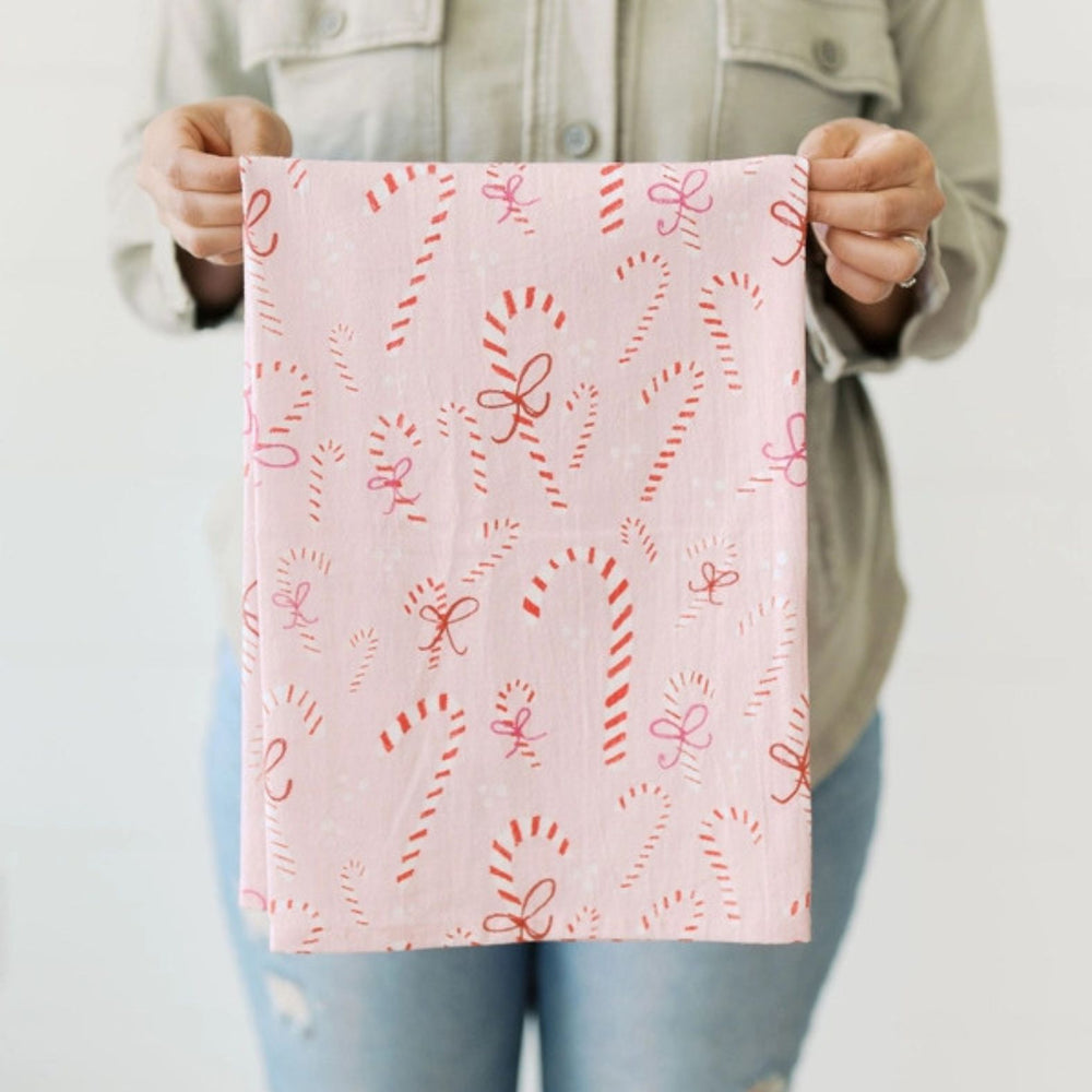 Person holding a Doe A Dear pink towel with red candy cane patterns against a neutral background | Build A Custom Christmas Gift Box with Luxe & Bloom