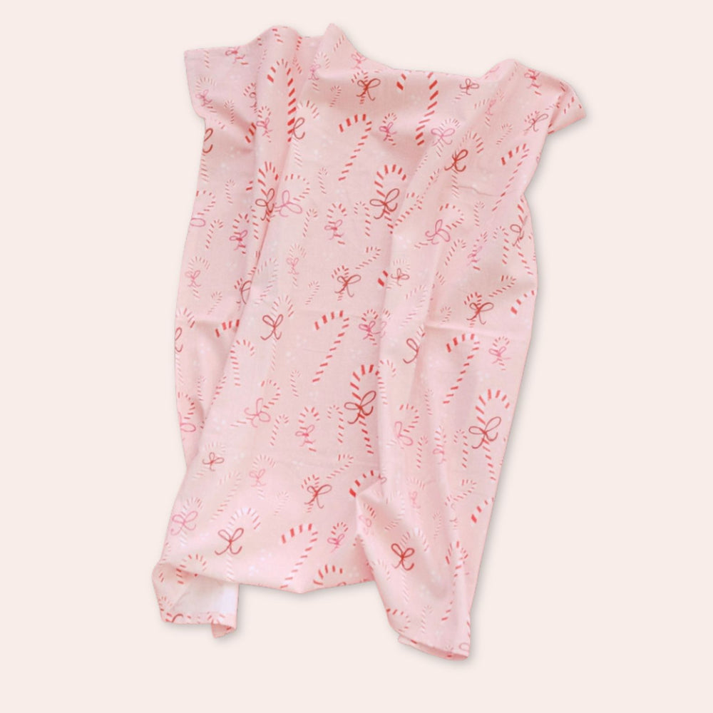 Person holding a Doe A Dear pink towel with red candy cane patterns against a neutral background | Build A Custom Christmas Gift Box with Luxe & Bloom