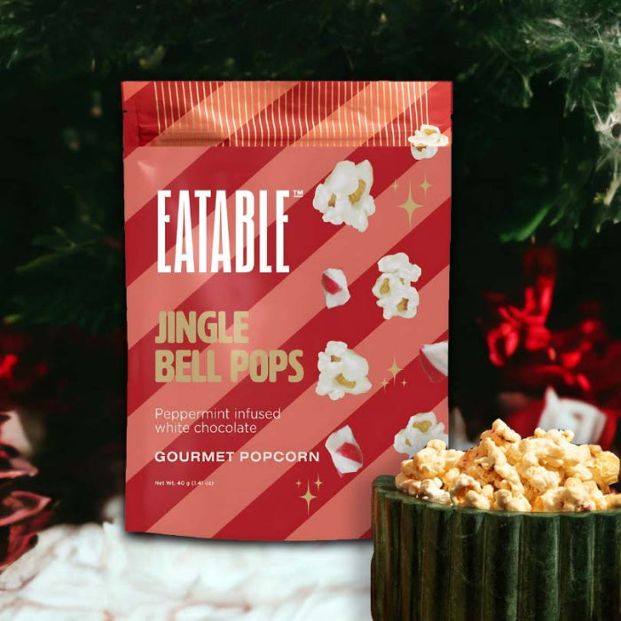 Eatable Jingle Bell Pops gourmet popcorn packaging with popcorn in a bowl against a festive background. Build a luxury custom Christmas gift box with Luxe & Bloom