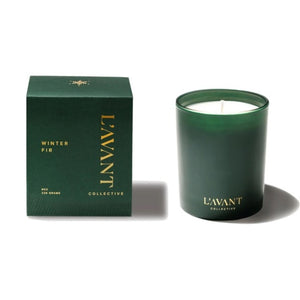 A dark green glass jar candle next to its matching dark green box packaging, both featuring gold lettering for the brand 'L'AVANT COLLECTIVE' and the scent name 'WINTER FIR'.