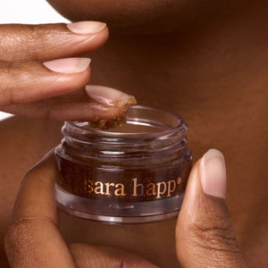 Hand applying a small jar of 'sara happ' brown sugar lip scrub | Build A Luxury Custom Gift Box for Women with Luxe & Bloom