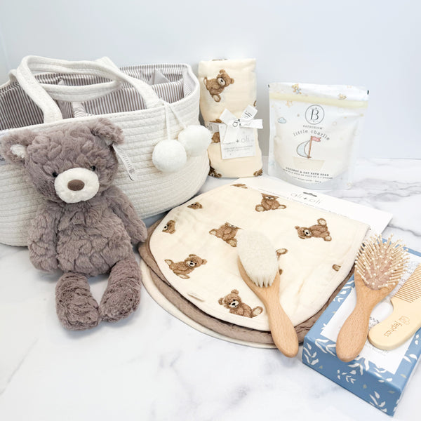Baby care products including a teddy bear, diaper caddy, and baby items on a light background